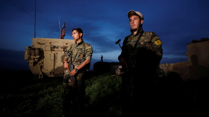 Kurdish fighters from the People's Protection Units (YPG) stand near a U.S military vehicle in the town of Darbasiya next to the Turkish border, Syria, on April 28, 2017.
