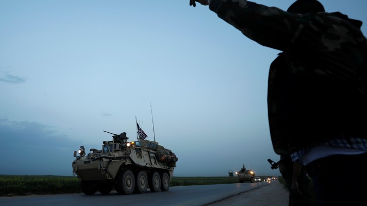 A Kurdish fighter from the People's Protection Units (YPG) gestures at a convoy of U.S military vehicles driving in the town of Darbasiya next to the Turkish border, Syria, on April 28, 2017.