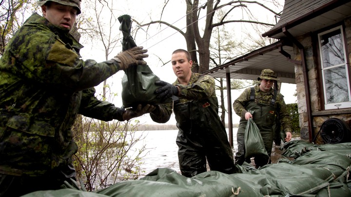 Canadian soldiers place sandbags outside a home in a flooded residential neighbourhood.