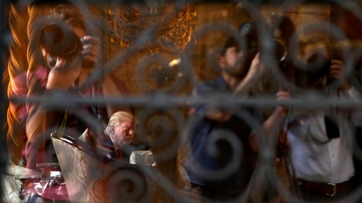 President Donald Trump, seen through a window at his Mar-a-Lago resort in Palm Beach, Florida