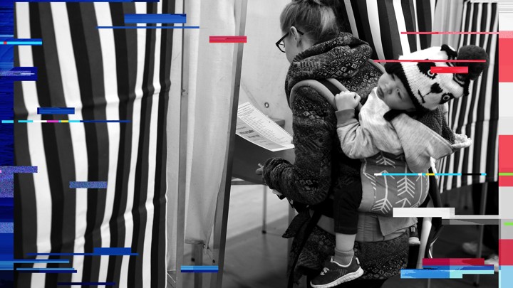 A woman with a child on her back prepares to mark her ballot in a voting booth in Bedford, New Hampshire, on February 9, 2016.