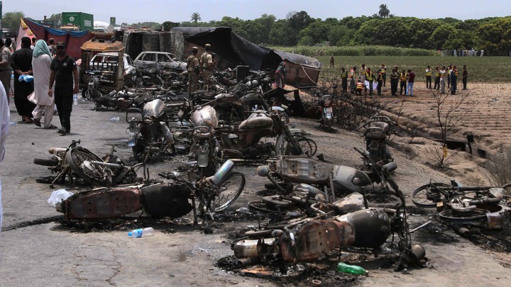 Pakistan army soldiers stands guard while rescue workers examine the site of an oil tanker explosion at a highway near Bahawalpur, Pakistan.