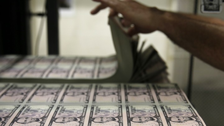Someone leafs through a pile of $5 bills