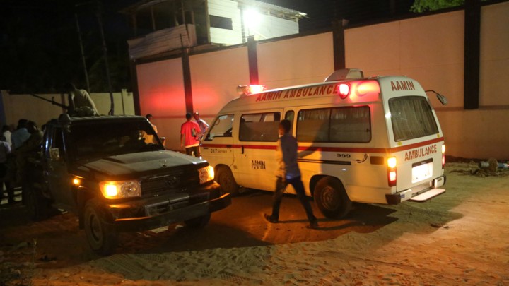 A man walks past an ambulance and armed security forces at the scene of an attack in Mogadishu, Somalia, on June 14, 2017.