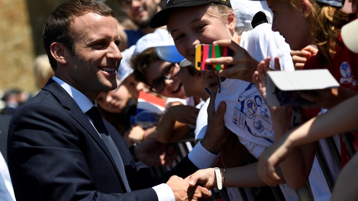 French President Emmanuel Macron shakes hands at a ceremony.
