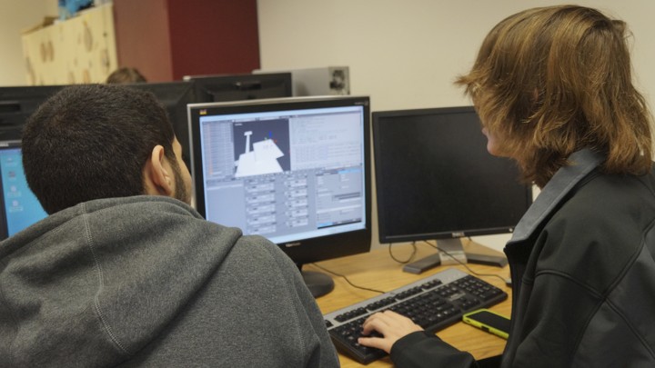 Taken from behind them, two young men stare at a computer screen