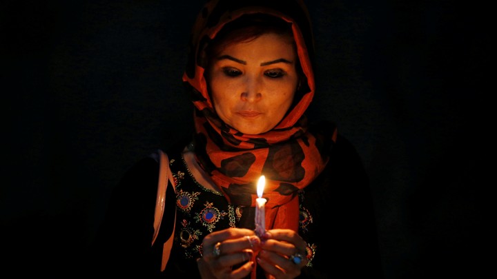 A woman holds a lit candle for the victims of Wednesday's blast in Kabul, Afghanistan.