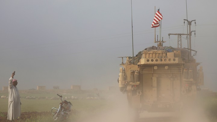 A man gestures at U.S military vehicles near the Turkish border of Syria on April 28, 2017.