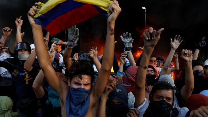Protesters react in front of the entrance of a building housing the magistracy of the Supreme Court of Justice and a bank branch during a rally on June 12, 2017.