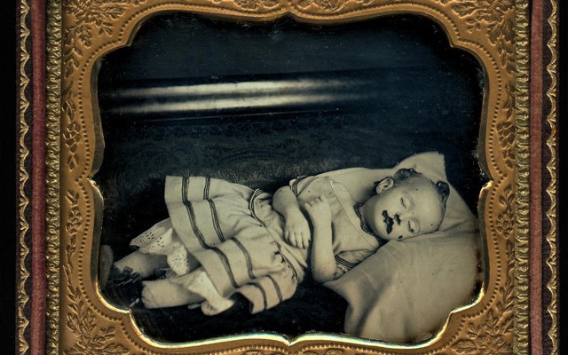 A framed black-and-white image of a deceased infant