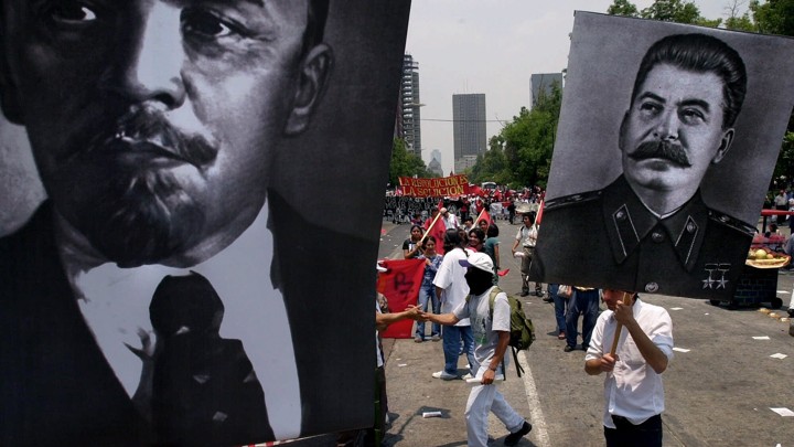 People in a demonstration carry posters with images of Lenin and Stalin.