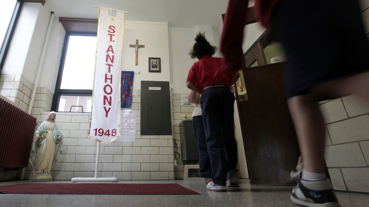 Students at a Catholic school pass a statue of the Virgin Mary and a crucifix on their way to class.