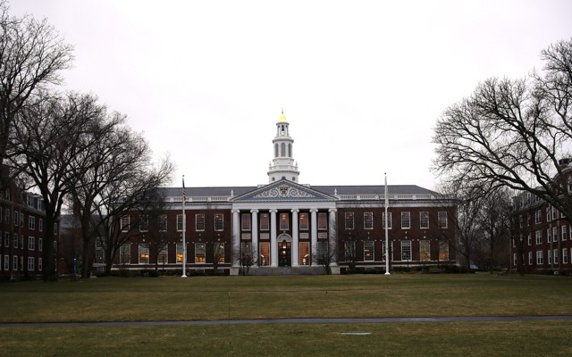 A library at Harvard is shown from afar with the lawn stretching in front of it