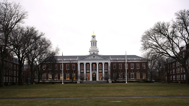 A library at Harvard is shown from afar with the lawn stretching in front of it