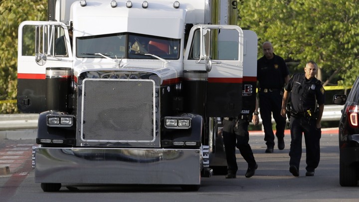 San Antonio police officers investigate the scene where eight people were found dead in a tractor-trailer loaded with at least 30 others outside a Walmart store in stifling summer heat in what police are calling a horrific human trafficking case.