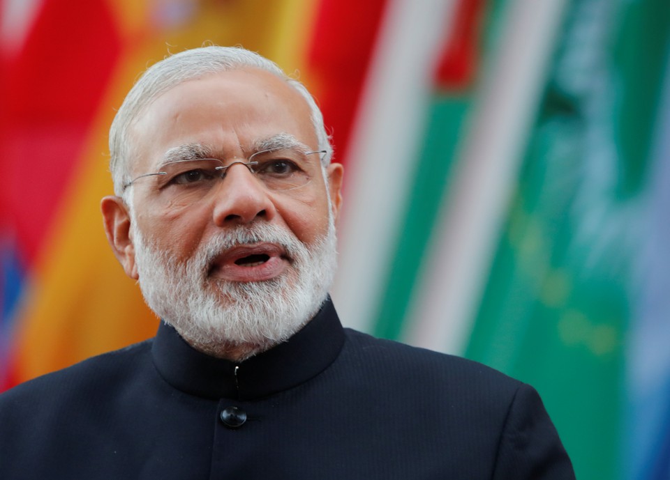 India's Prime Minister Narendra Modi looking at the camera in front of a row of flags.