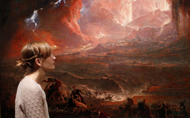 A woman stands next to an apocalyptic painting—John Martin's "The Destruction of Pompeii and Herculaneum"—in Tate Britain, London.