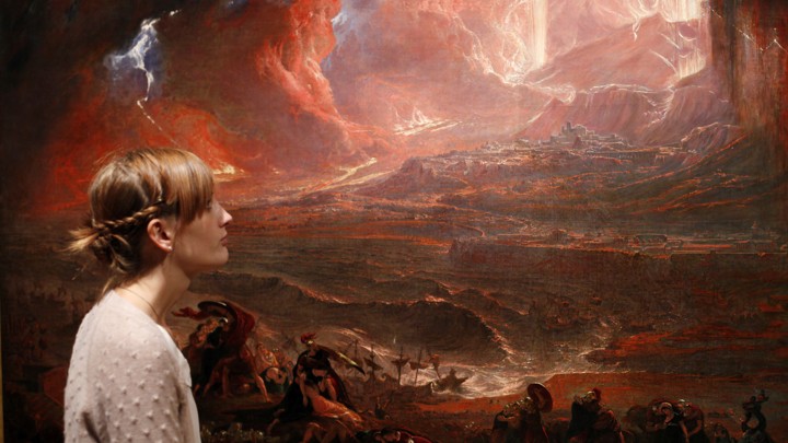 A woman stands next to an apocalyptic painting—John Martin's "The Destruction of Pompeii and Herculaneum"—in Tate Britain, London.