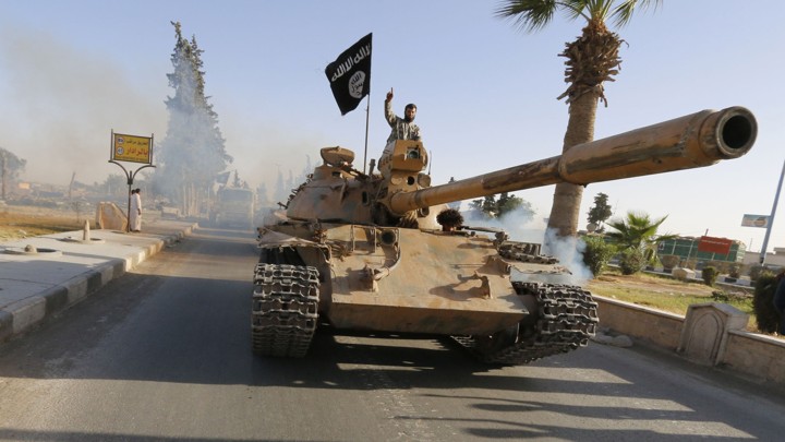 An ISIS fighter rolls down a street of Raqqa in a military tank.
