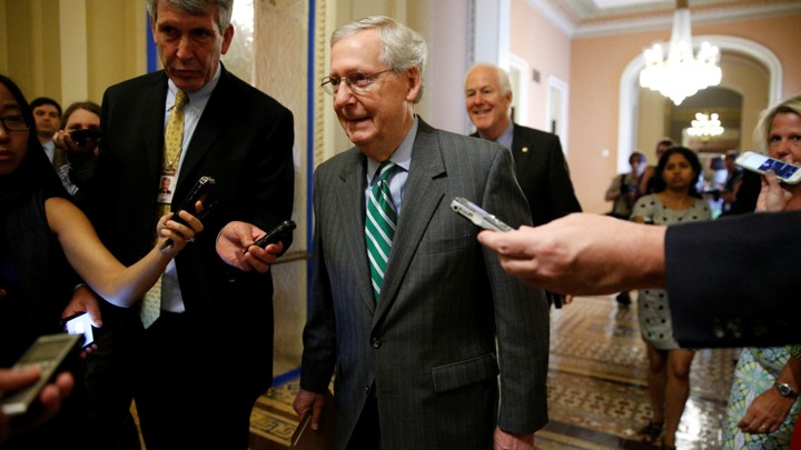 Majority Leader Mitch McConnell walks alongside reporters on Capitol Hill.