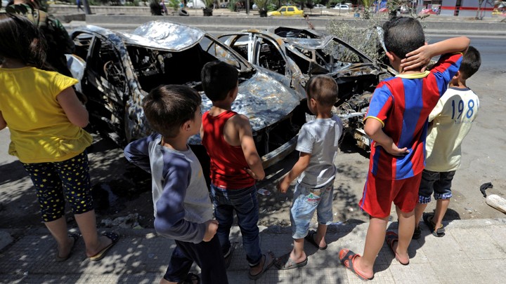 Children look at the wreckage of vehicles at a blast site in the Baytara traffic circle near the Old City of Damascus, Syria.