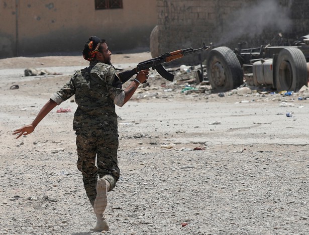 A Kurdish fighter from the People's Protection Units (YPG) fires his rifle at Islamic State militants as he runs across a street in Raqqa, Syria.