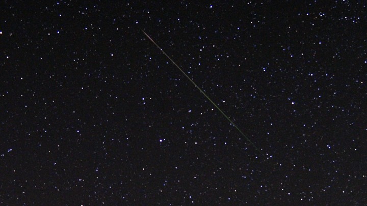 A thin diagonal line of light is shown against a starry sky.