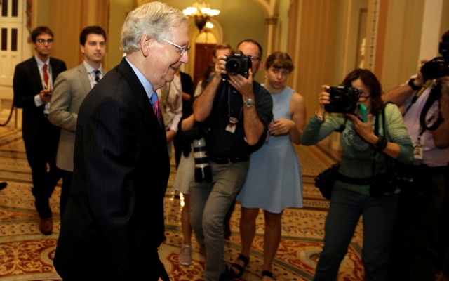 Senate Majority Leader Mitch McConnell walks down a hallway in a Capitol Hill building.
