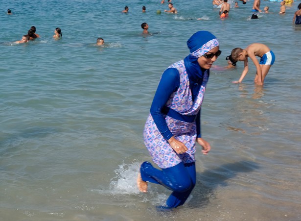 A woman wearing a burqini walks in the water on a beach in France.