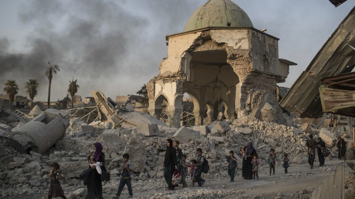 Fleeing Iraqi civilians walk past the damaged al-Nuri mosque as Iraqi forces continue their advance against ISIS militants in Mosul on July 4, 2017.