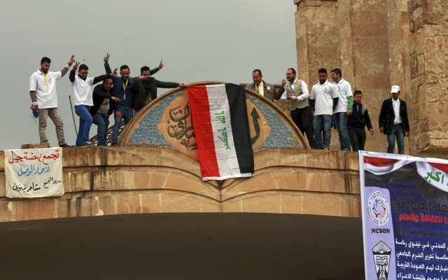 Mosul University students and activists place a national flag at the entrance of their university as they celebrate its liberation from ISIS.