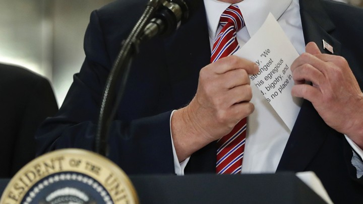 President Trump reaches for a prepared statement in his pocket