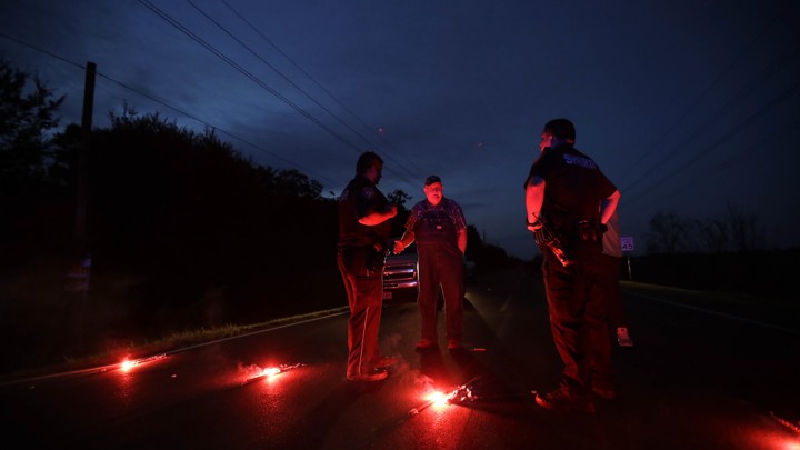 Police officers stand around a row of flares.