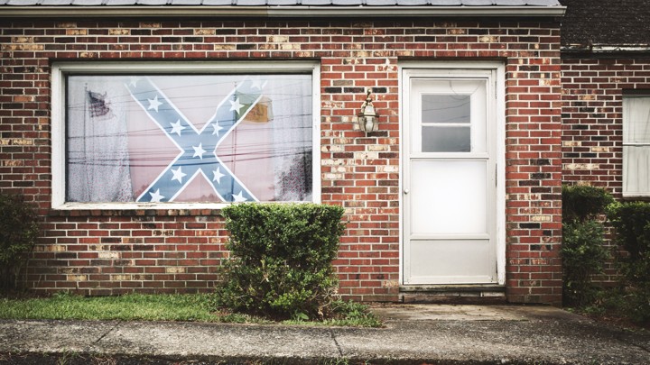 A Confederate flag hangs in the window of a house.