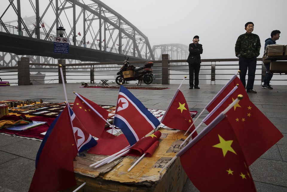 Chinese vendors sell North Korea and China flags on the boardwalk next to a bridge that connects China and North Korea.