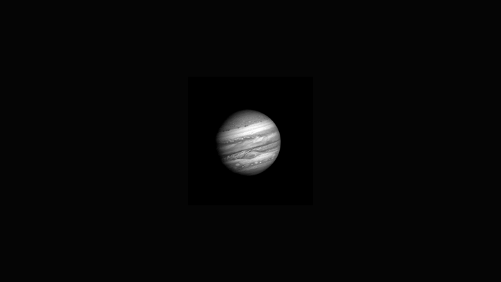 A gif of Jupiter and its stormy atmosphere in black and white, steadily growing larger
