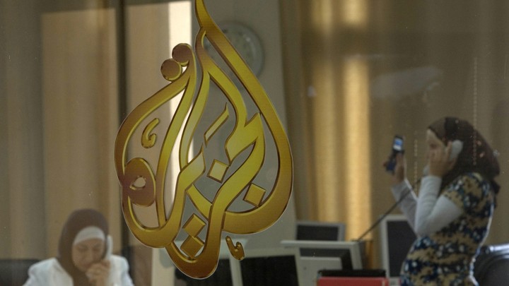 Palestinian journalists are seen through a window at the Al-Jazeera offices in the West Bank city of Ramallah on July 15, 2009
