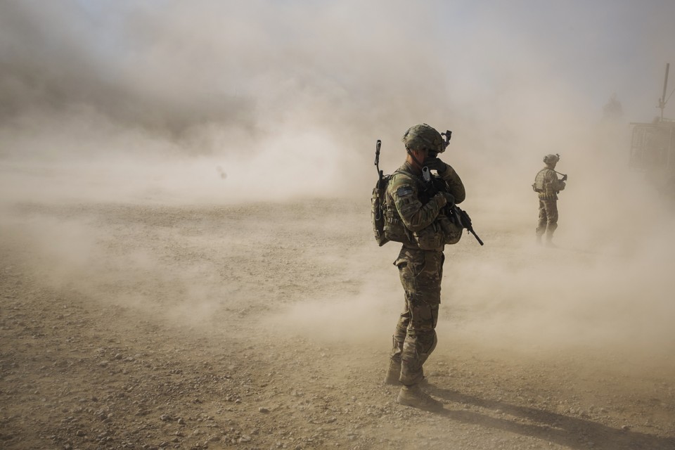 U.S. soldiers cover their faces from the dust blown around by the rotors of a helicopter. 