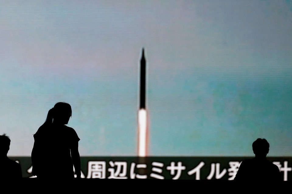 People walk in front of a monitor showing news of North Korea's fresh threat in Tokyo