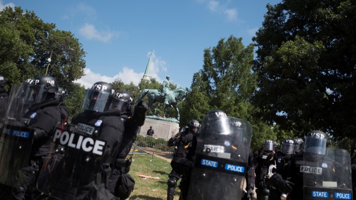 Riot police stand in formation in Charlottesville with a statue of Robert E. Lee behind them.