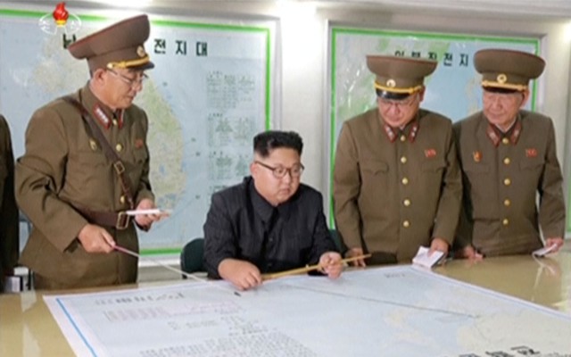 Kim Jong Un and his military advisers examine a large map