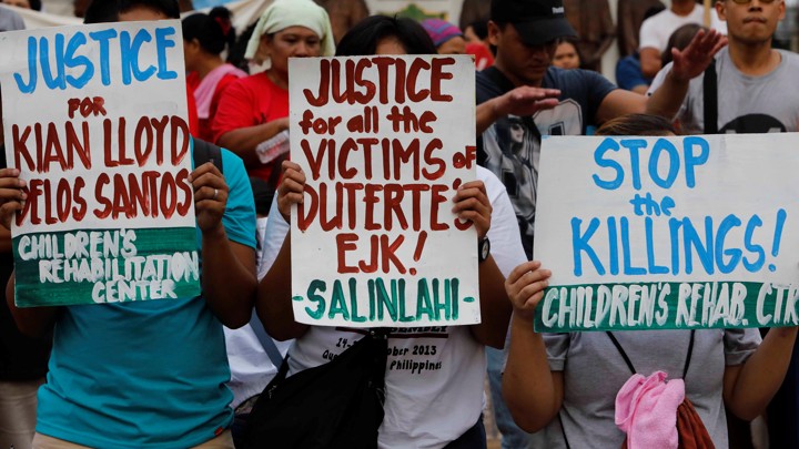 Activists display placards during a rally after 91 people were shot dead in the Philippines.