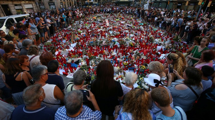 People gathered around a memorial made of flowers.