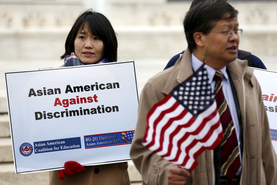 Two Asians hold signs opposing racial discrimination in college admissions outside the Supreme Court