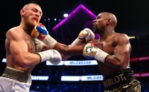 Floyd Mayweather Jr. lands a hit against Conor McGregor during a boxing match. 