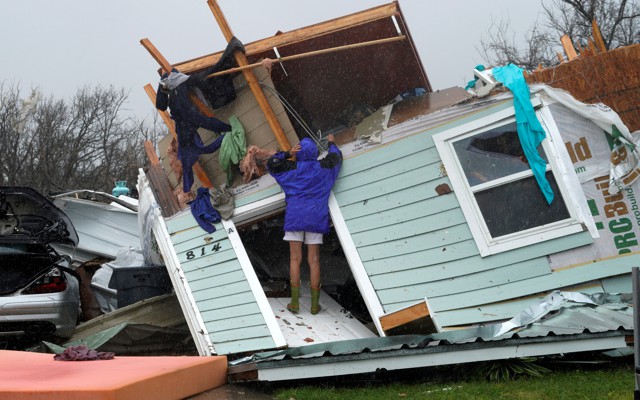A woman stands on a destroyed house in Fulton, Texas.