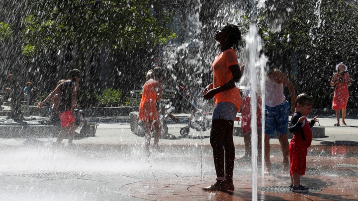 A girl plays near a water fountain on a summer day.