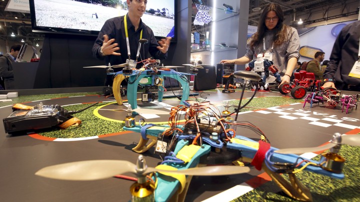 Two people stand next to a 3D-printed drone, which sits on a table.