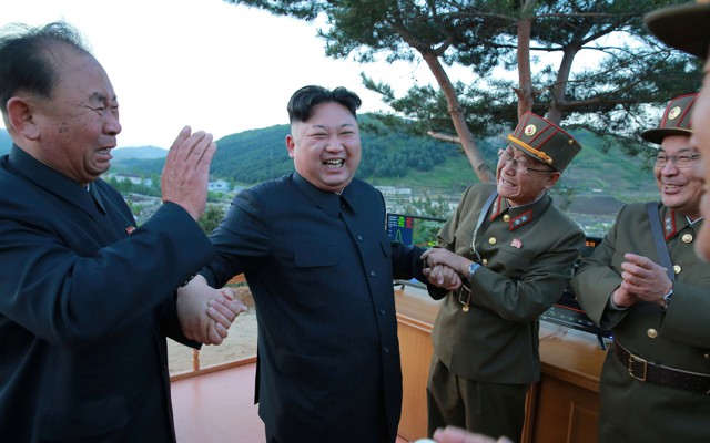 North Korean leader Kim Jong Un reacts with scientists and engineers.