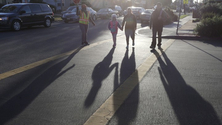 Parents cross the street with their children.